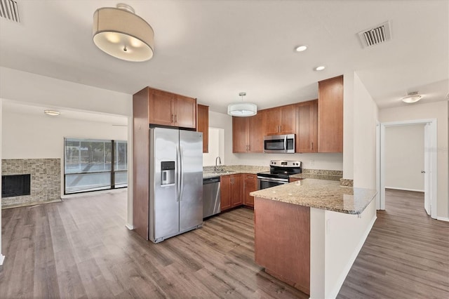 4907 4th Avenue Cir NW, Bradenton, FL 34209 - kitchen featuring a peninsula, brown cabinets, wood finished floors, visible vents, and appliances with stainless steel finishes