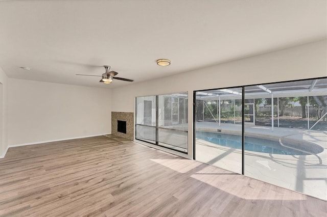 4907 4th Avenue Cir NW, Bradenton, FL 34209 - unfurnished living room with baseboards, ceiling fan, a sunroom, wood finished floors, and a fireplace