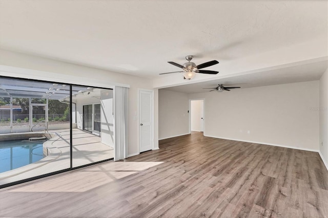 4907 4th Avenue Cir NW, Bradenton, FL 34209 - unfurnished living room with a sunroom, baseboards, a ceiling fan, and wood finished floors