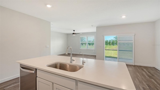 kitchen with a sink, dark wood-type flooring, dishwasher, light countertops, and baseboards