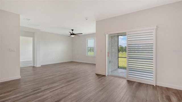 interior space with a ceiling fan, baseboards, visible vents, and wood finished floors