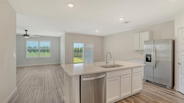 kitchen featuring a sink, stainless steel appliances, white cabinets, light wood-type flooring, and light countertops