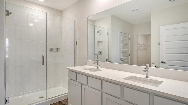 bathroom featuring visible vents, a shower stall, a spacious closet, and a sink