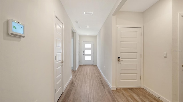 corridor featuring visible vents, light wood-style flooring, and baseboards