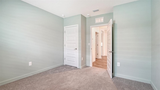 unfurnished bedroom with carpet floors, baseboards, and visible vents