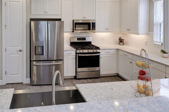 5301 Bartolomeo St, Sarasota, FL 34238 - kitchen with appliances with stainless steel finishes, a sink, decorative backsplash, and white cabinets