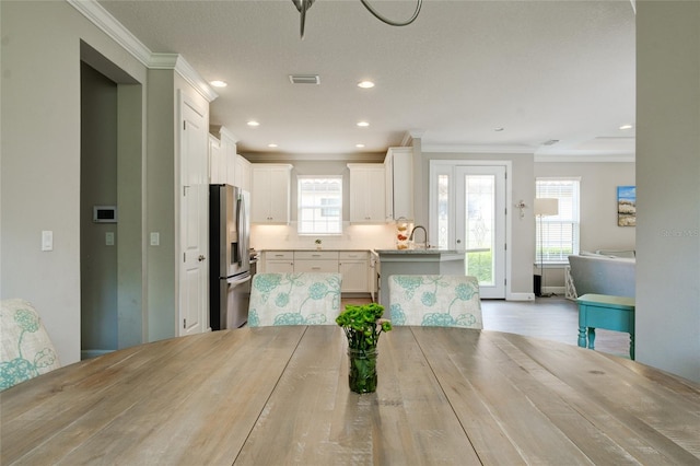 5301 Bartolomeo St, Sarasota, FL 34238 - kitchen featuring stainless steel fridge with ice dispenser, crown molding, a sink, white cabinetry, and recessed lighting