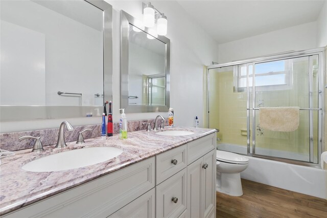 3105 Gulfgate Dr, Sarasota, FL 34231 - bathroom with toilet, double vanity, combined bath / shower with glass door, and wood finished floors
