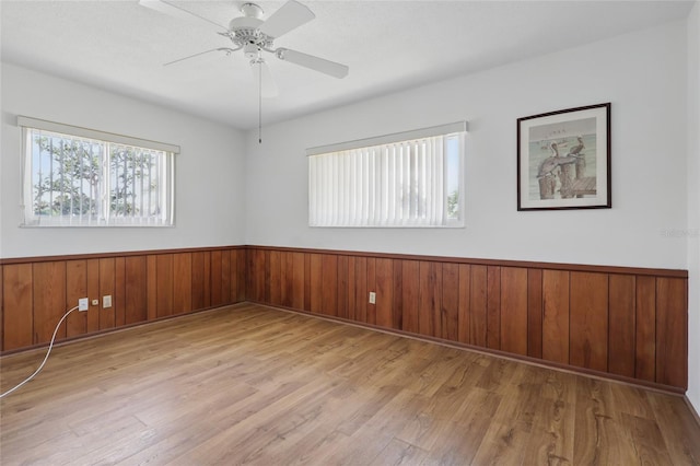 3105 Gulfgate Dr, Sarasota, FL 34231 - empty room with wood finished floors, a wainscoted wall, ceiling fan, and wood walls