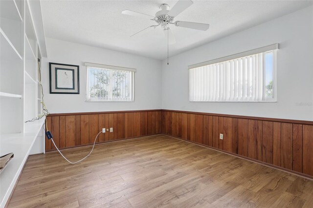3105 Gulfgate Dr, Sarasota, FL 34231 - spare room with a wainscoted wall, wood finished floors, wooden walls, and a ceiling fan