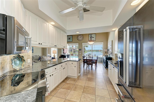 13167 Fernando St, Venice, FL 34293 - kitchen with appliances with stainless steel finishes, white cabinets, a tray ceiling, a ceiling fan, and tasteful backsplash