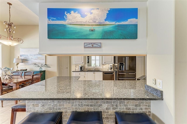 13167 Fernando St, Venice, FL 34293 - kitchen with appliances with stainless steel finishes, a sink, a breakfast bar area, a peninsula, and dark stone counters
