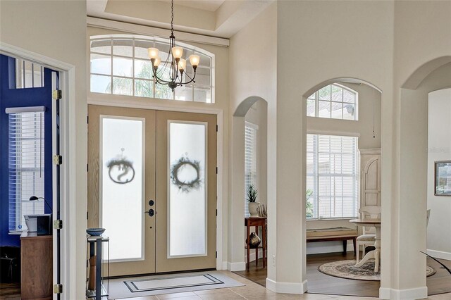8103 Snowy Egret Pl, Bradenton, FL 34202 - foyer entrance with french doors, arched walkways, a towering ceiling, a chandelier, and baseboards