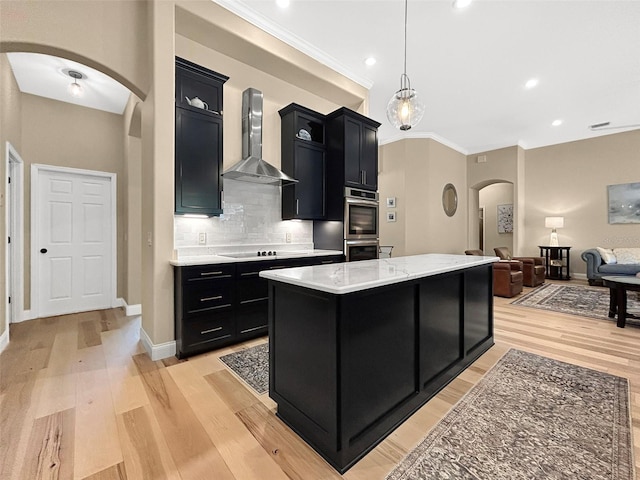 6567 Eagle Ridge Way, Lakeland, FL 33813 - kitchen with arched walkways, dark cabinetry, wall chimney exhaust hood, a center island, and light wood-style floors