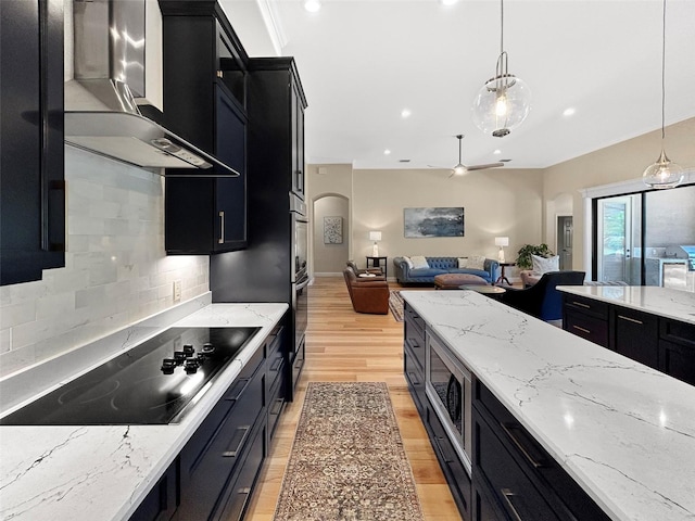 6567 Eagle Ridge Way, Lakeland, FL 33813 - kitchen with dark cabinetry, stainless steel appliances, wall chimney exhaust hood, open floor plan, and light wood-type flooring