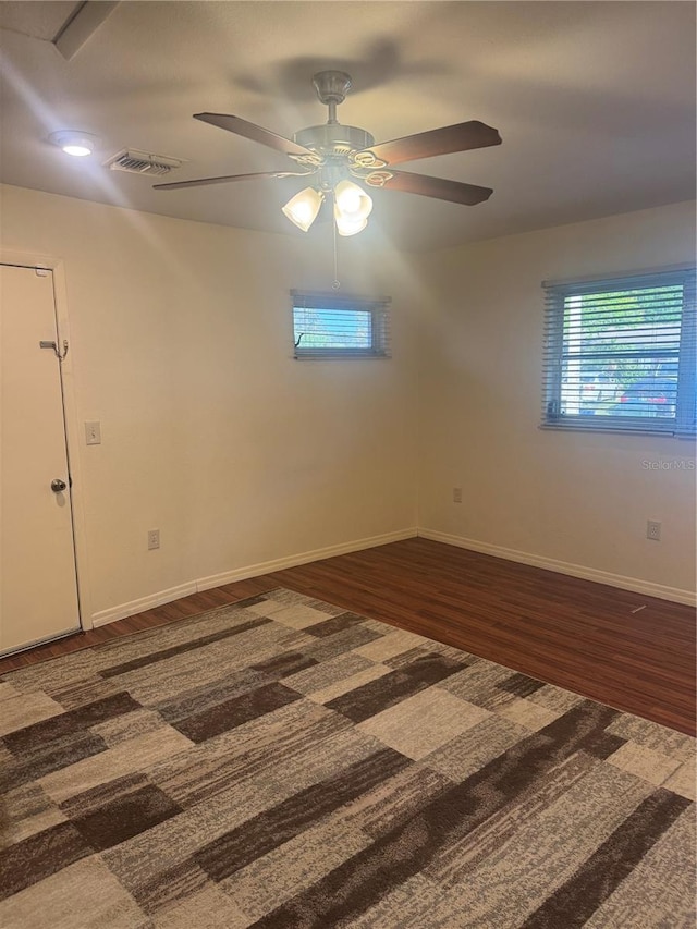 unfurnished room featuring baseboards, visible vents, ceiling fan, and wood finished floors