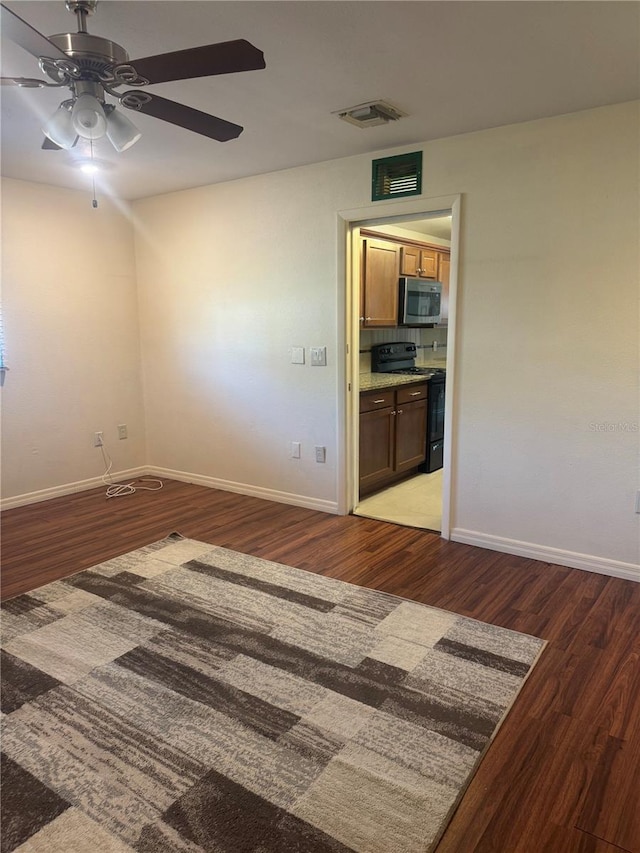 empty room featuring ceiling fan, baseboards, and wood finished floors