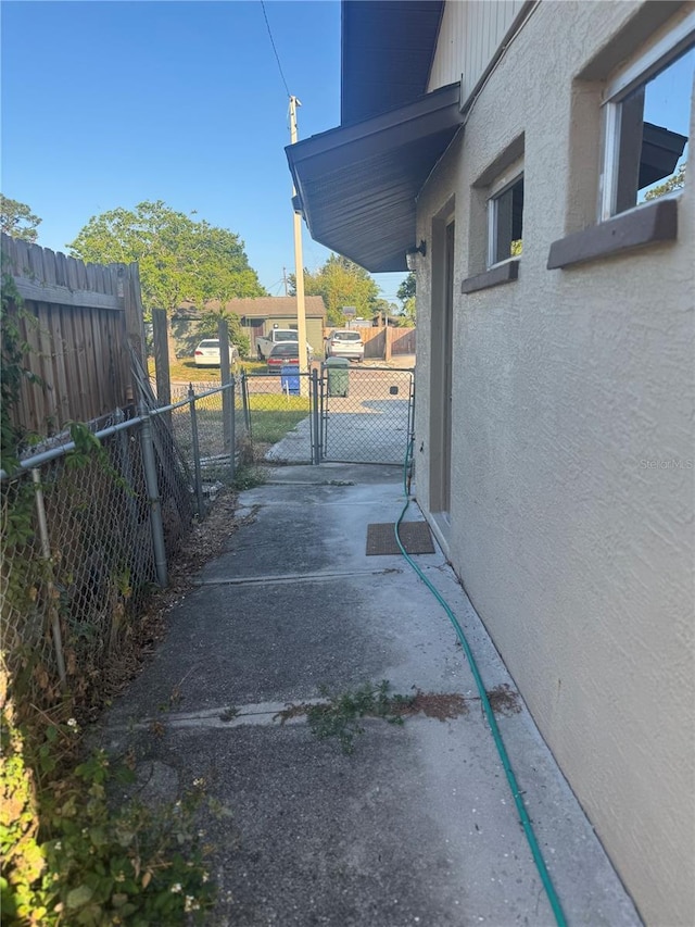 view of property exterior with stucco siding, a gate, and fence