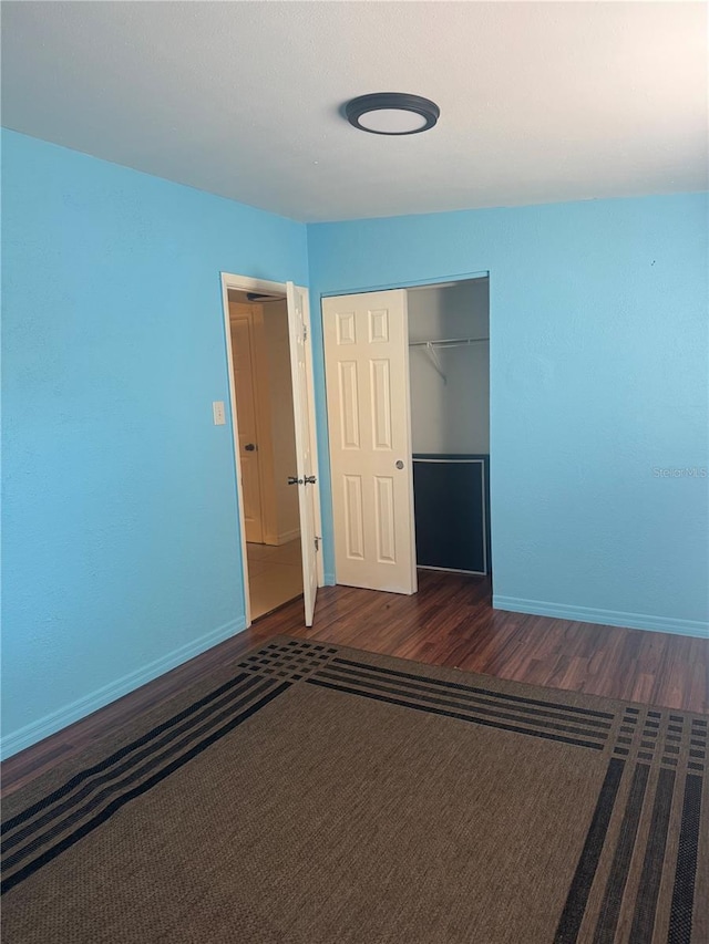 unfurnished bedroom with a closet, baseboards, and wood finished floors