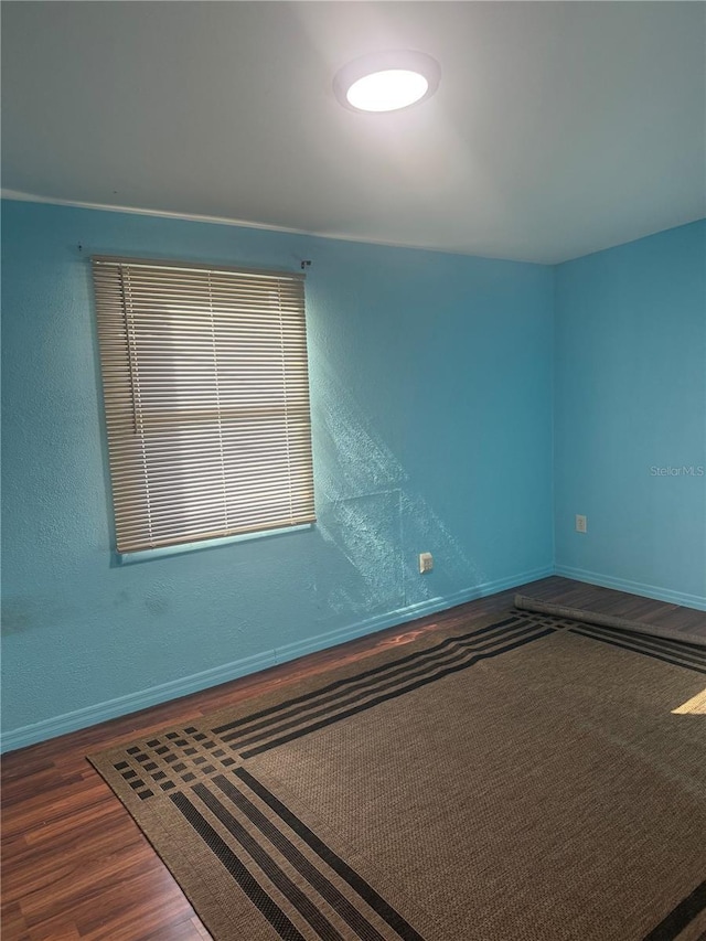 unfurnished room with baseboards and wood finished floors