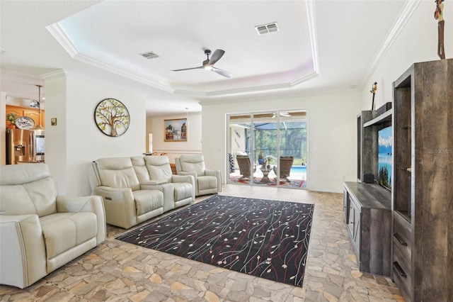 living area featuring a tray ceiling, crown molding, a ceiling fan, and visible vents