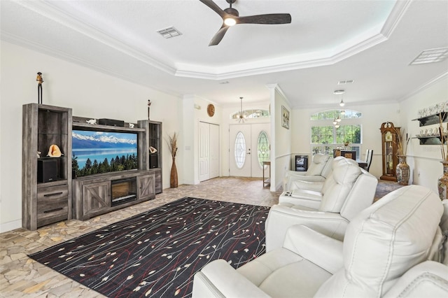 living room featuring ornamental molding, a raised ceiling, a ceiling fan, and visible vents