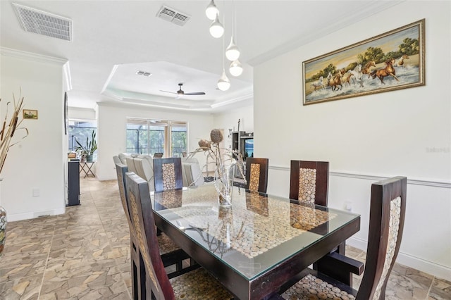 dining space with ceiling fan, a raised ceiling, and visible vents