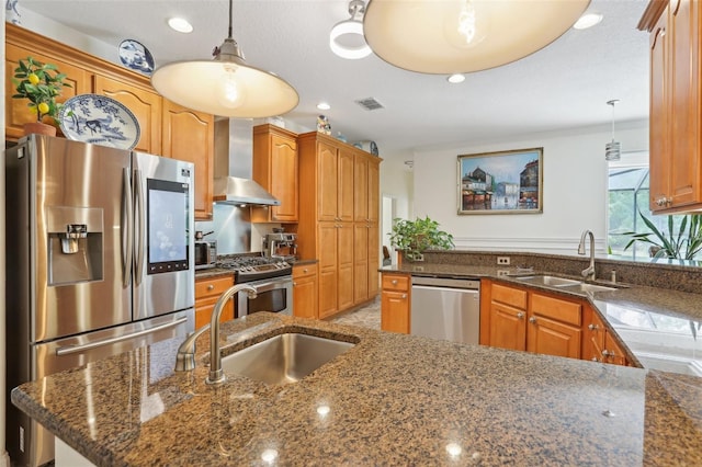 kitchen with a sink, stainless steel appliances, wall chimney range hood, and recessed lighting