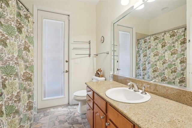 bathroom featuring toilet, vanity, and curtained shower