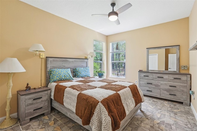 bedroom with baseboards, a ceiling fan, and stone finish floor