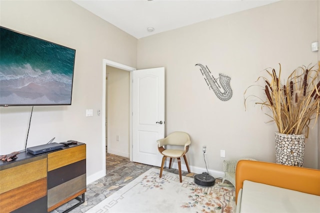 sitting room with baseboards and stone finish floor