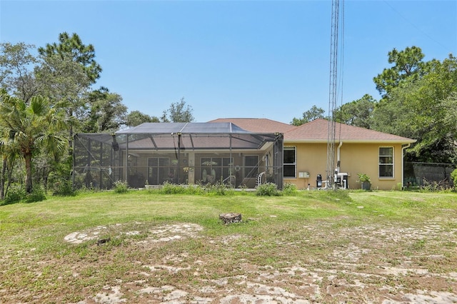 back of house featuring a yard, stucco siding, and a lanai