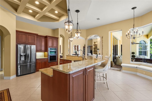 6143 9th Avenue Cir NE, Bradenton, FL 34212 - kitchen featuring stainless steel appliances, arched walkways, decorative columns, light tile patterned floors, and beam ceiling