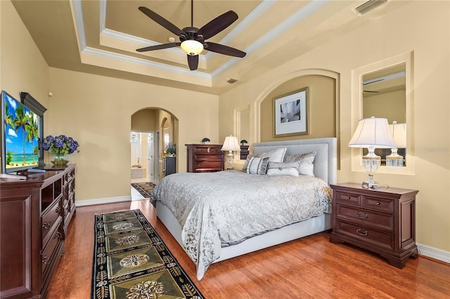 6143 9th Avenue Cir NE, Bradenton, FL 34212 - bedroom featuring arched walkways, a tray ceiling, wood finished floors, crown molding, and baseboards