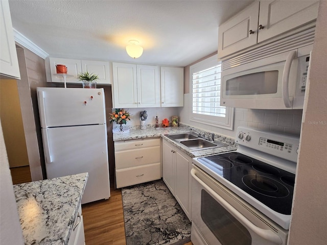 kitchen featuring a sink, white appliances, wood finished floors, light stone counters, and white cabinets