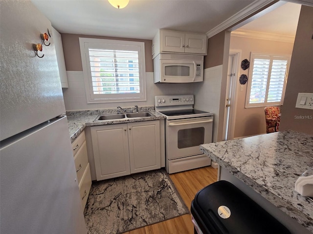kitchen with white appliances, light wood finished floors, white cabinets, and a sink