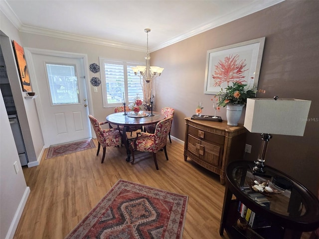 dining room featuring baseboards, light wood finished floors, a chandelier, and crown molding
