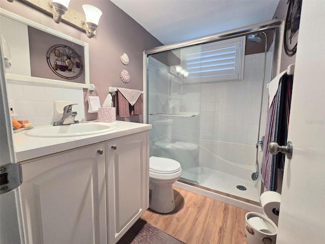 full bath with a stall shower, vanity, toilet, and wood finished floors