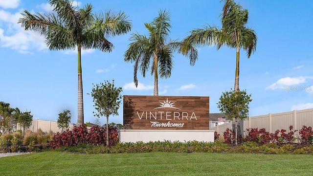 community sign with fence and a lawn