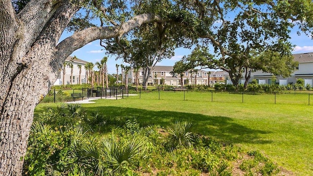 view of community featuring fence, a lawn, and a residential view