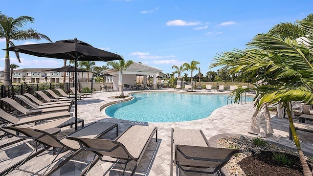 community pool with a patio area and fence