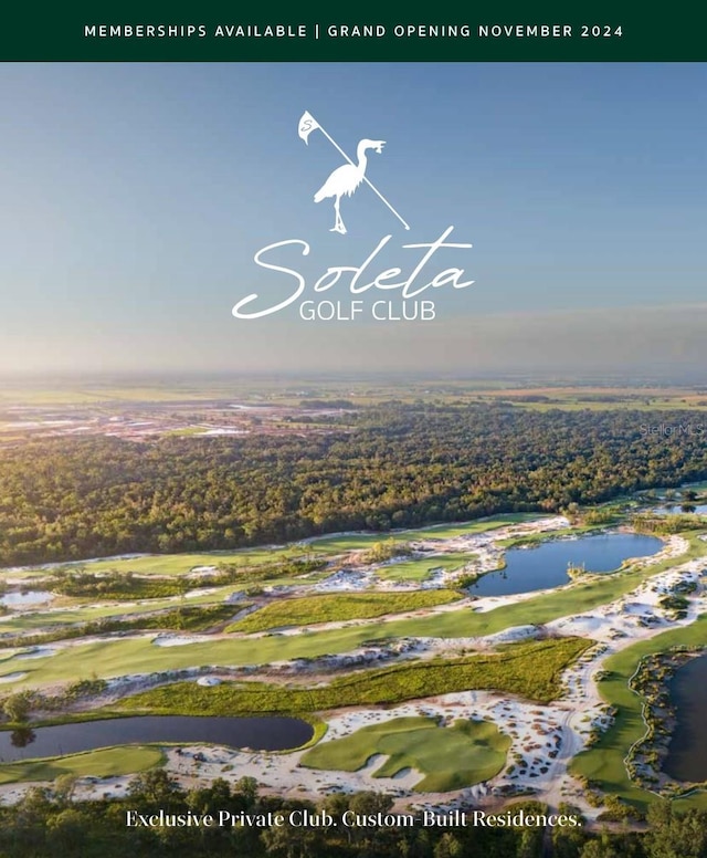 aerial view of property and surrounding area with a nearby body of water and a golf club