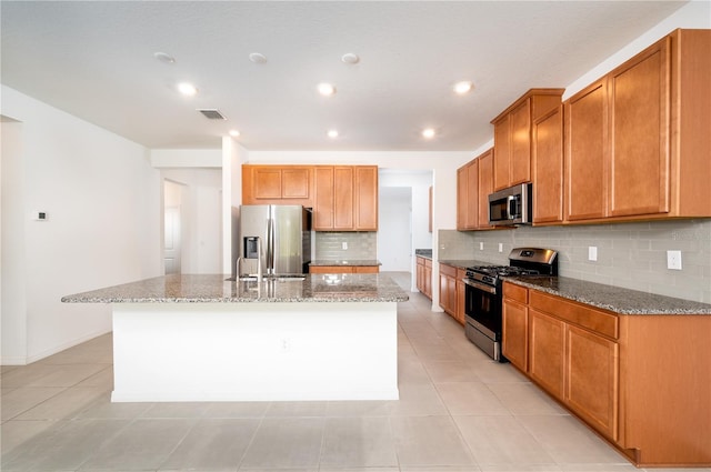 10171 Milky Way Cir, Sarasota, FL 34241 - kitchen featuring stainless steel appliances, a kitchen island with sink, visible vents, tasteful backsplash, and light stone counters