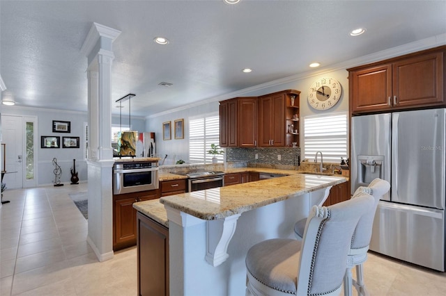212 River Enclave Ct, Bradenton, FL 34212 - kitchen with stainless steel appliances, ornate columns, a peninsula, a center island, and crown molding