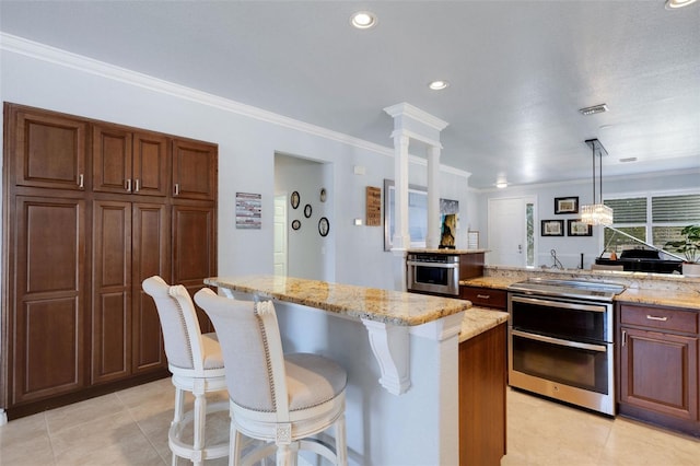 212 River Enclave Ct, Bradenton, FL 34212 - kitchen with wall oven, a breakfast bar area, ornamental molding, light stone countertops, and a kitchen island