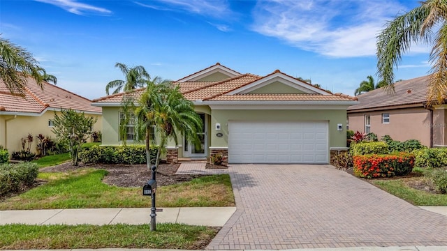 212 River Enclave Ct, Bradenton, FL 34212 - view of front facade with a garage, stucco siding, decorative driveway, a tile roof, and stone siding