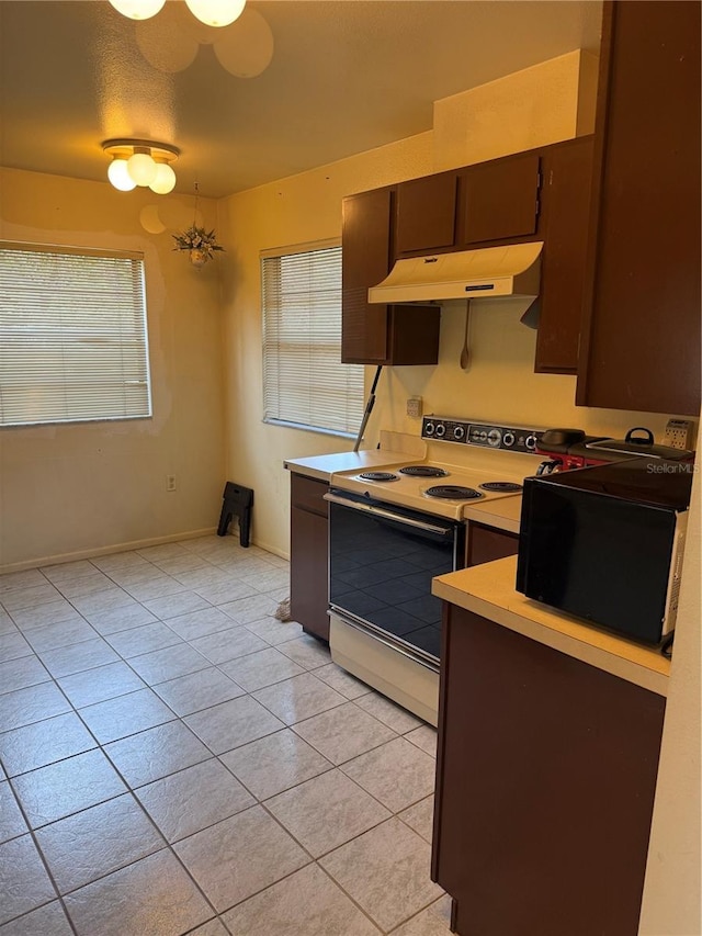 5014 Barrington Cir Unit 2102, Sarasota, FL 34234 - kitchen with under cabinet range hood, electric stove, black microwave, light countertops, and light tile patterned flooring