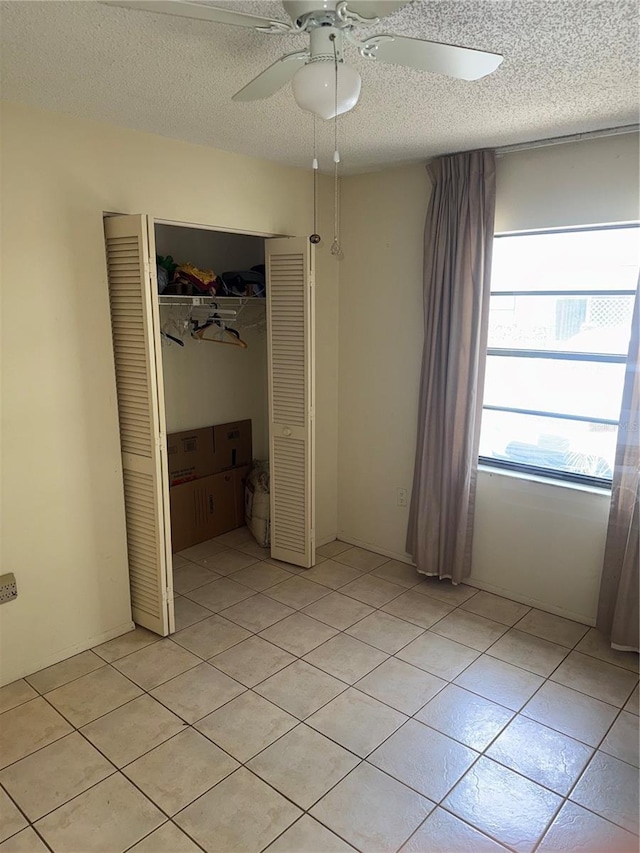 5014 Barrington Cir Unit 2102, Sarasota, FL 34234 - unfurnished bedroom featuring a textured ceiling, a closet, a ceiling fan, and light tile patterned floors