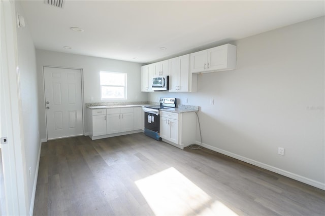 1208 SE Mills Ave, Arcadia, FL 34266 - kitchen featuring stainless steel appliances, white cabinetry, light wood finished floors, and baseboards