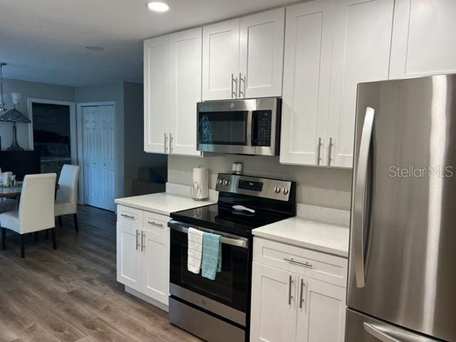 2726 Knoll St E, Palm Harbor, FL 34683 - kitchen featuring stainless steel appliances, light countertops, wood finished floors, white cabinets, and recessed lighting
